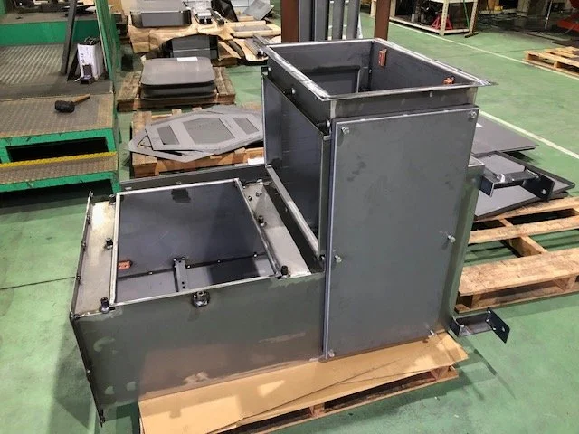 用途別に仕分けされた板金加工製品が棚と作業台に並ぶ様子